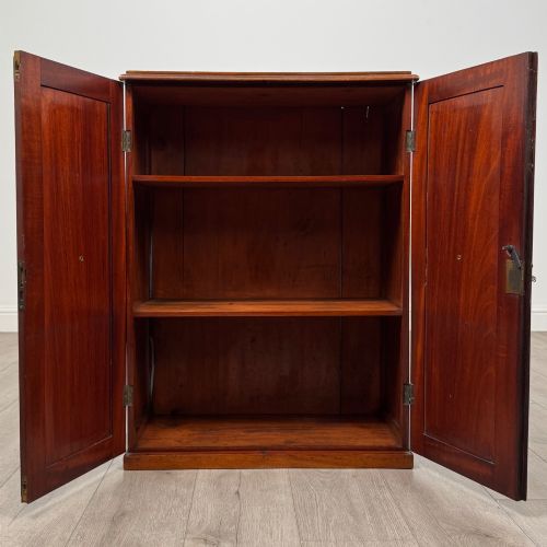 fig 1. A small Victorian mahogany double-door cupboard featuring raised central panels, green circular brass flower mounts, and a decorative central keyhole.