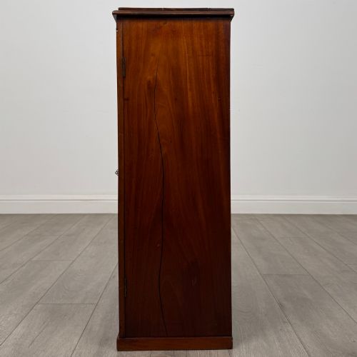 fig 3. A small Victorian mahogany double-door cupboard featuring raised central panels, green circular brass flower mounts, and a decorative central keyhole.