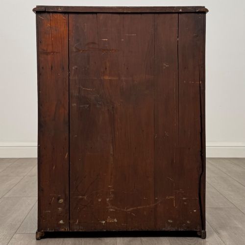 fig 5. A small Victorian mahogany double-door cupboard featuring raised central panels, green circular brass flower mounts, and a decorative central keyhole.