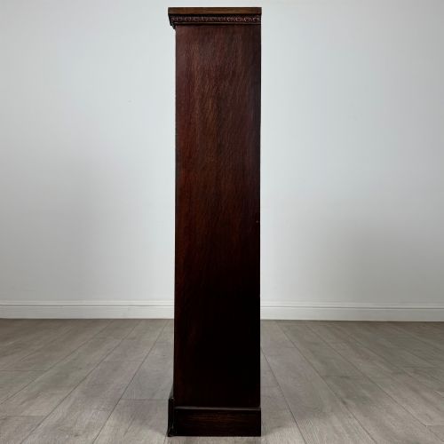 fig 3. An Edwardian open oak bookcase featuring three interior fixed shelves, dark timber finish, carved moulding on top uprights, and a shaped plinth base.