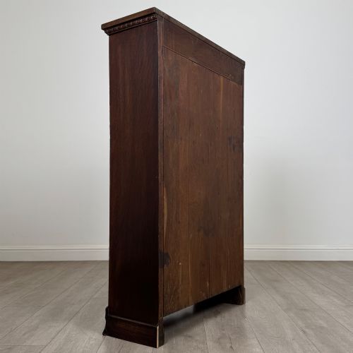 fig 4. An Edwardian open oak bookcase featuring three interior fixed shelves, dark timber finish, carved moulding on top uprights, and a shaped plinth base.