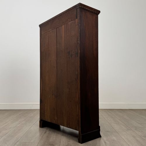 fig 6. An Edwardian open oak bookcase featuring three interior fixed shelves, dark timber finish, carved moulding on top uprights, and a shaped plinth base.