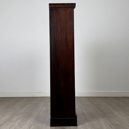 fig 7. An Edwardian open oak bookcase featuring three interior fixed shelves, dark timber finish, carved moulding on top uprights, and a shaped plinth base.