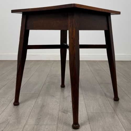 fig 3. An antique dark oak Edwardian side table featuring four tapered legs, an X-shaped lower stretcher, and a square top surface.