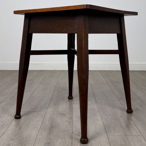 fig 5. An antique dark oak Edwardian side table featuring four tapered legs, an X-shaped lower stretcher, and a square top surface.