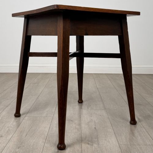 fig 7. An antique dark oak Edwardian side table featuring four tapered legs, an X-shaped lower stretcher, and a square top surface.