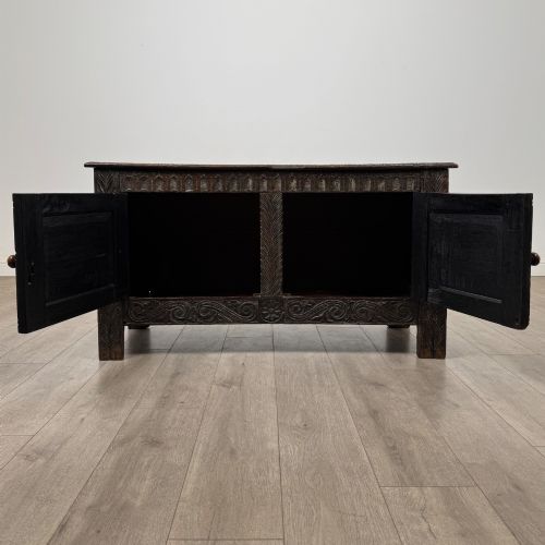 fig 1. A low dark oak Victorian cupboard featuring two doors with relief carvings of birds and flowers, flanked by leafy carved uprights and a carved frieze.