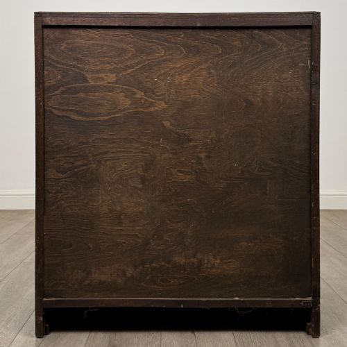 fig 4. A dark oak chest of drawers featuring carved vertical linenfold panels and metallic drop handles.