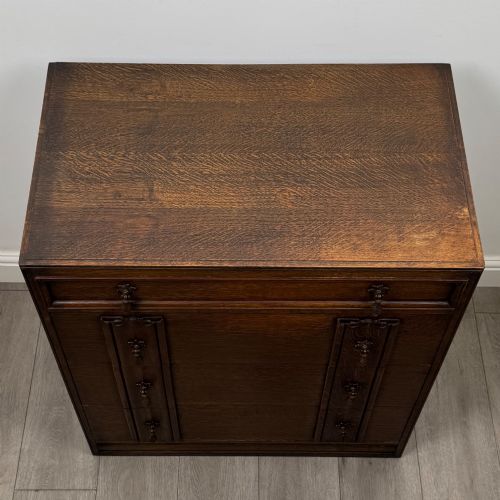 fig 8. A dark oak chest of drawers featuring carved vertical linenfold panels and metallic drop handles.