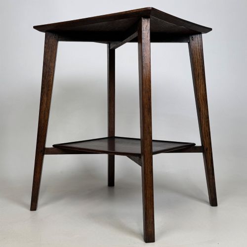 fig 1. An Edwardian dark oak side table featuring a square top, cross-stretchers, tapered legs, and a lower square shelf.