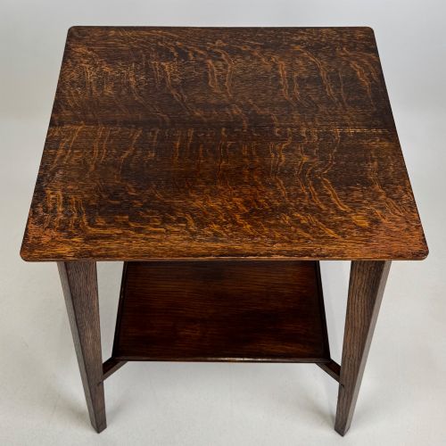 fig 8. An Edwardian dark oak side table featuring a square top, cross-stretchers, tapered legs, and a lower square shelf.
