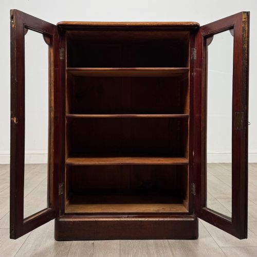 fig 1. A nineteenth-century mahogany display cabinet featuring twin glazed doors with arched framing and a plinth base.