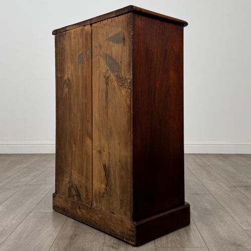 fig 6. A nineteenth-century mahogany display cabinet featuring twin glazed doors with arched framing and a plinth base.