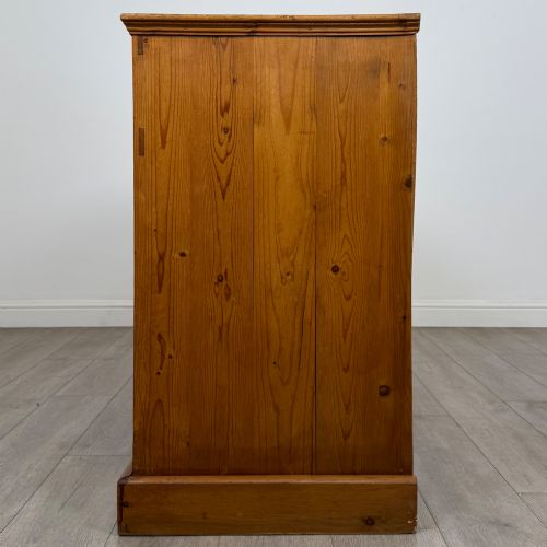 fig 3. A vintage pine farmhouse sideboard featuring three frieze drawers above three panelled cupboard doors with turned wooden knobs on a plinth base.