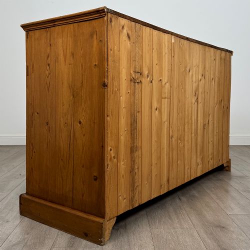 fig 4. A vintage pine farmhouse sideboard featuring three frieze drawers above three panelled cupboard doors with turned wooden knobs on a plinth base.