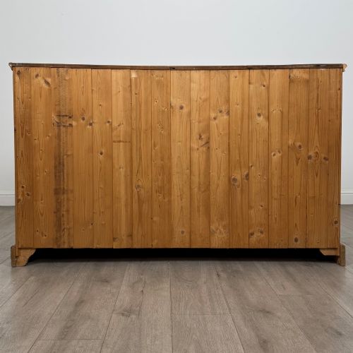 fig 5. A vintage pine farmhouse sideboard featuring three frieze drawers above three panelled cupboard doors with turned wooden knobs on a plinth base.