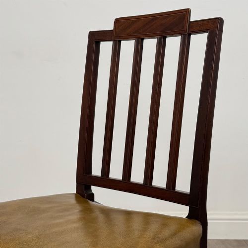 fig 3. A set of six antique mahogany dining chairs featuring vertical slat backs, square legs, and olive green leather seats finished with brass studs.