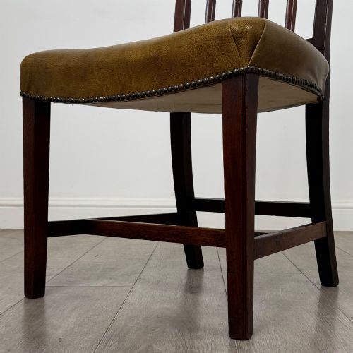 fig 5. A set of six antique mahogany dining chairs featuring vertical slat backs, square legs, and olive green leather seats finished with brass studs.