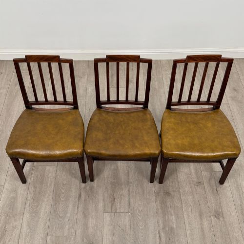 fig 6. A set of six antique mahogany dining chairs featuring vertical slat backs, square legs, and olive green leather seats finished with brass studs.