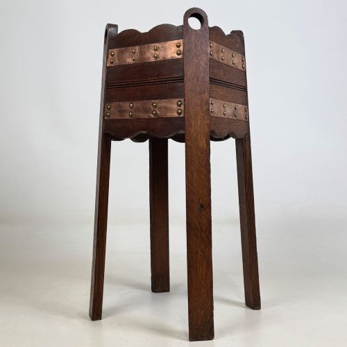 fig 5. An antique Arts and Crafts dark oak plant stand featuring copper straps with brass rivets, pierced handles, and scalloped edges.
