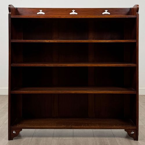 fig 1. An early 20th-century Arts and Crafts open walnut bookcase featuring four shelves and decorative pierced cut-outs on the top gallery and plinth base.