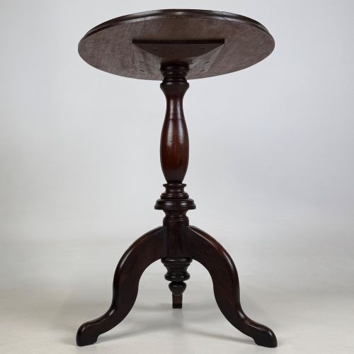 fig 2. An antique dark mahogany side table featuring a smooth oval top, a centrally turned pedestal stem, and three splayed tripod legs.