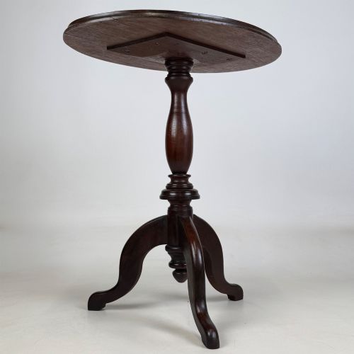 fig 3. An antique dark mahogany side table featuring a smooth oval top, a centrally turned pedestal stem, and three splayed tripod legs.