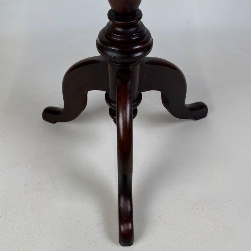 fig 6. An antique dark mahogany side table featuring a smooth oval top, a centrally turned pedestal stem, and three splayed tripod legs.