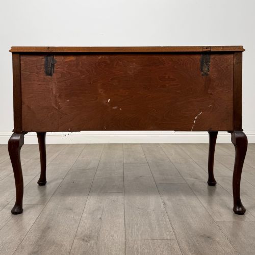 fig 4. A 20th-century walnut writing table featuring four drawers, decorative brass drop handles, an arched kneehole centre, and curved cabriole legs.