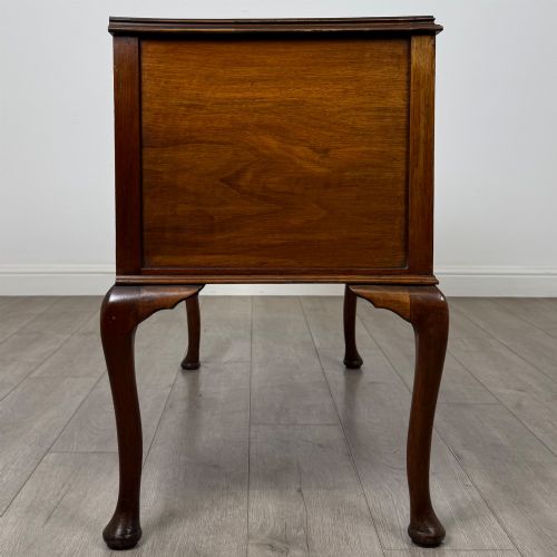 fig 6. A 20th-century walnut writing table featuring four drawers, decorative brass drop handles, an arched kneehole centre, and curved cabriole legs.