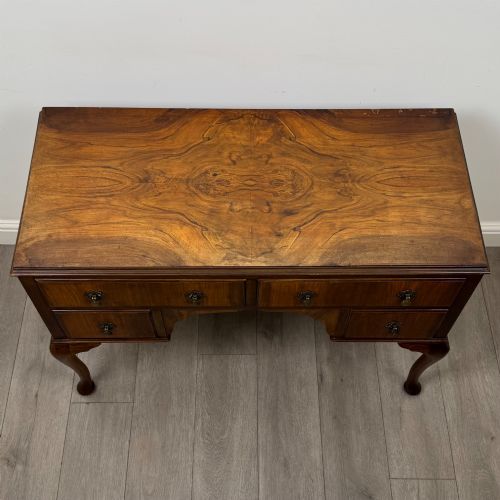 fig 8. A 20th-century walnut writing table featuring four drawers, decorative brass drop handles, an arched kneehole centre, and curved cabriole legs.