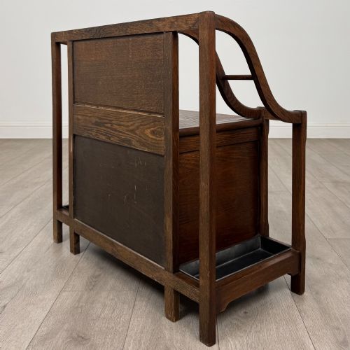 fig 5. An antique Edwardian golden oak hall seat featuring a central panelled backrest and integrated side umbrella stands with metal drip trays.