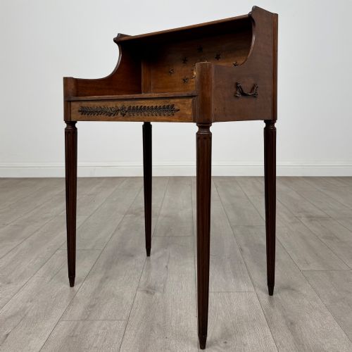 fig 1. A French mahogany side table featuring slim tapered fluted legs, a carved laurel motif apron, and a gallery back adorned with brass stars.