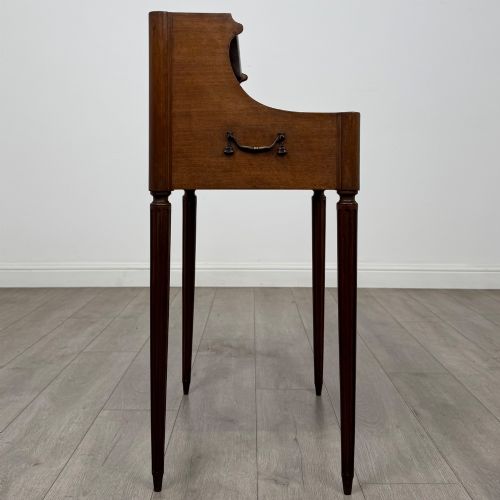 fig 6. A French mahogany side table featuring slim tapered fluted legs, a carved laurel motif apron, and a gallery back adorned with brass stars.
