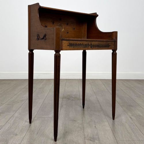 fig 7. A French mahogany side table featuring slim tapered fluted legs, a carved laurel motif apron, and a gallery back adorned with brass stars.