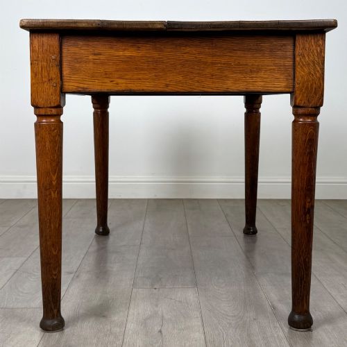 fig 2. An antique early 20th-century oak writing table featuring two front drawers with brass cup handles and turned legs.