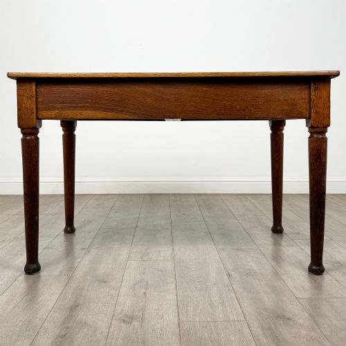 fig 4. An antique early 20th-century oak writing table featuring two front drawers with brass cup handles and turned legs.