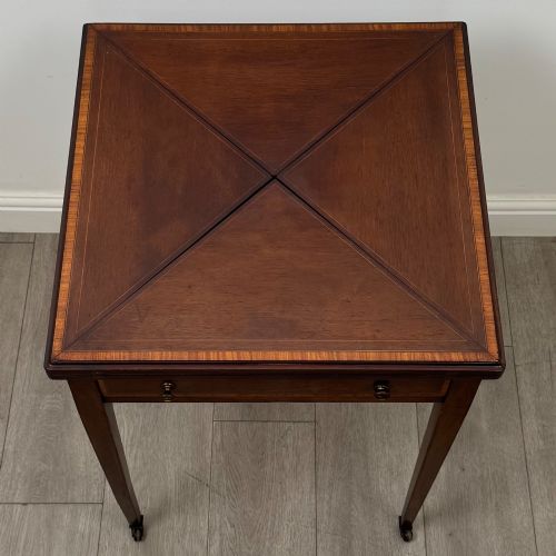 fig 8. An Edwardian mahogany envelope card table with crossbanded satinwood inlay, a single drawer, and tapered square legs on brass castors.