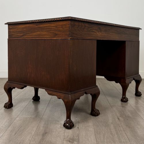 fig 3. An antique oak pedestal desk featuring twin drawer pedestals, carved borders, and cabriole legs terminating in ball-and-claw feet.