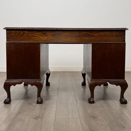 fig 4. An antique oak pedestal desk featuring twin drawer pedestals, carved borders, and cabriole legs terminating in ball-and-claw feet.