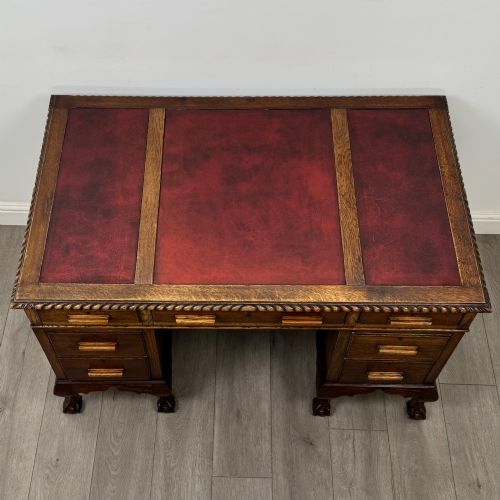 fig 8. An antique oak pedestal desk featuring twin drawer pedestals, carved borders, and cabriole legs terminating in ball-and-claw feet.