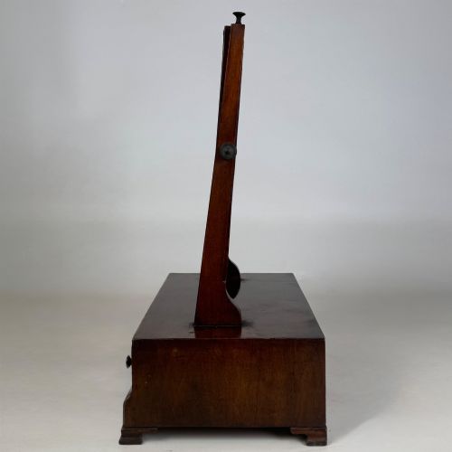 fig 2. An 18th-century Georgian mahogany dressing mirror featuring an adjustable rectangular tilting glass plate supported above a shaped box base containing three small drawers.