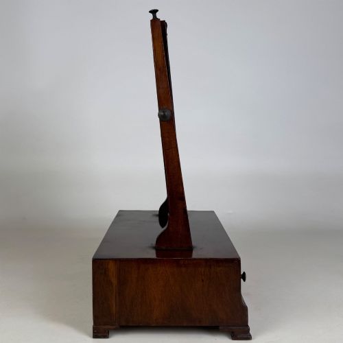 fig 6. An 18th-century Georgian mahogany dressing mirror featuring an adjustable rectangular tilting glass plate supported above a shaped box base containing three small drawers.