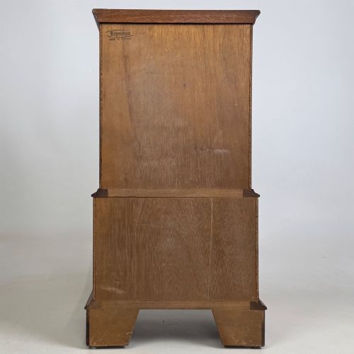fig 4. A small yew wood chest of drawers featuring a stepped tallboy structure with brass ring handles and bracket feet.