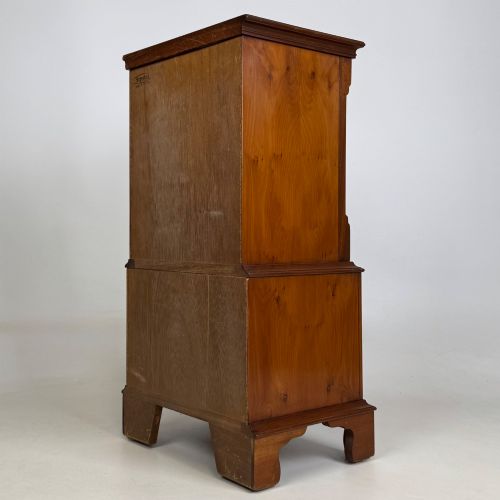 fig 5. A small yew wood chest of drawers featuring a stepped tallboy structure with brass ring handles and bracket feet.