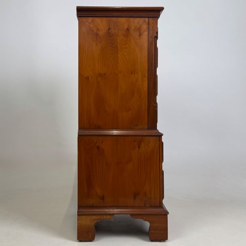 fig 6. A small yew wood chest of drawers featuring a stepped tallboy structure with brass ring handles and bracket feet.
