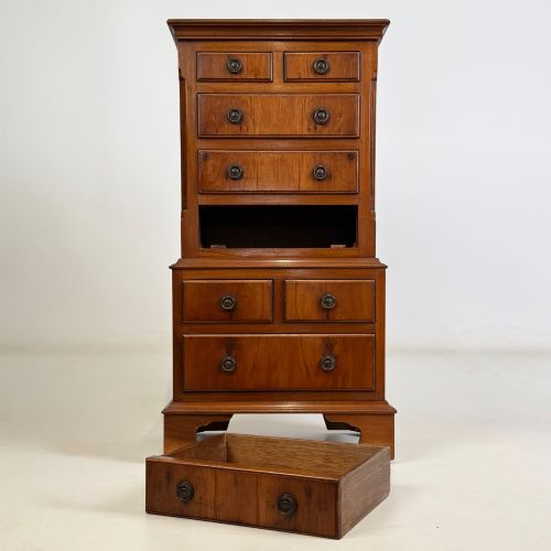fig 8. A small yew wood chest of drawers featuring a stepped tallboy structure with brass ring handles and bracket feet.