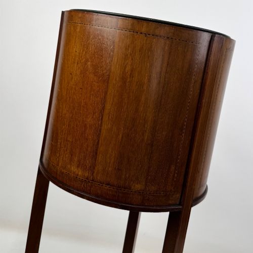 fig 5. A tall Edwardian mahogany plant stand featuring a cylindrical top bucket with subtle line inlay, supported by three elongated curved legs and a triangular lower shelf.
