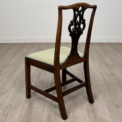 fig 2. A set of six Georgian mahogany dining chairs featuring intricate carved pierced splat backs, square legs, and light green patterned upholstered seats.
