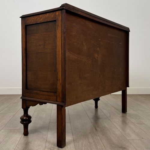fig 4. A dark oak sideboard featuring two carved drawers above a double-door cupboard resting on turned legs.
